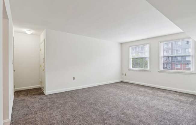 a living room with carpet and two windows