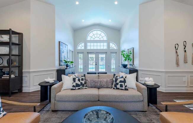 A living room with a couch, a coffee table, and a large window.