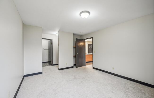 a empty living room with white walls and a door to a bathroom