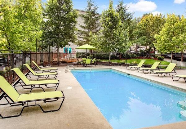 a swimming pool with lawn chairs around it