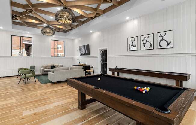 A pool table is in the middle of a room with a wooden floor and a wooden ceiling.