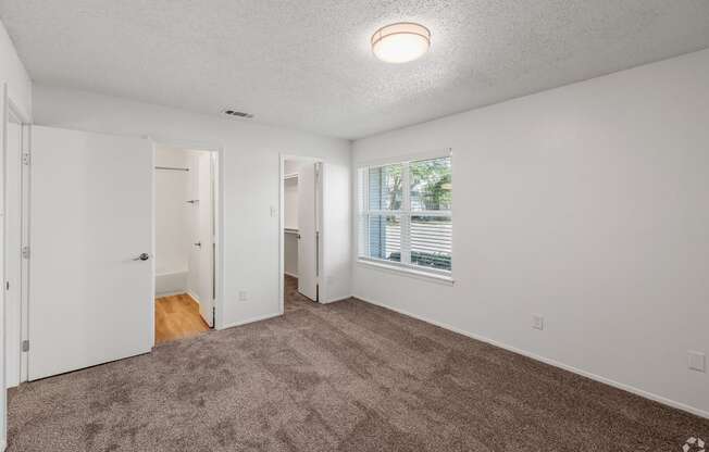 an empty living room with carpet and a window