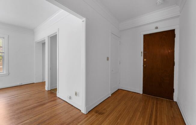 a bedroom with hardwood floors and white walls