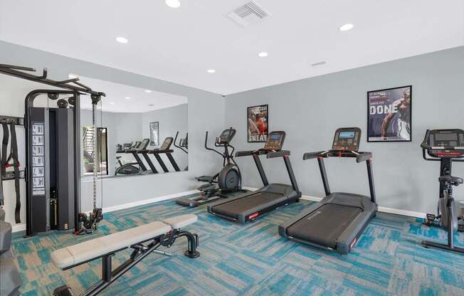 A gym with treadmilers, weights, and exercise equipment.