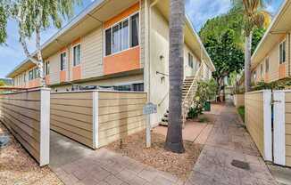 A small house with a brown roof and a white fence.