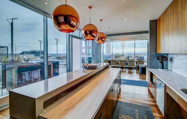 A modern kitchen with a long counter and pendant lights.