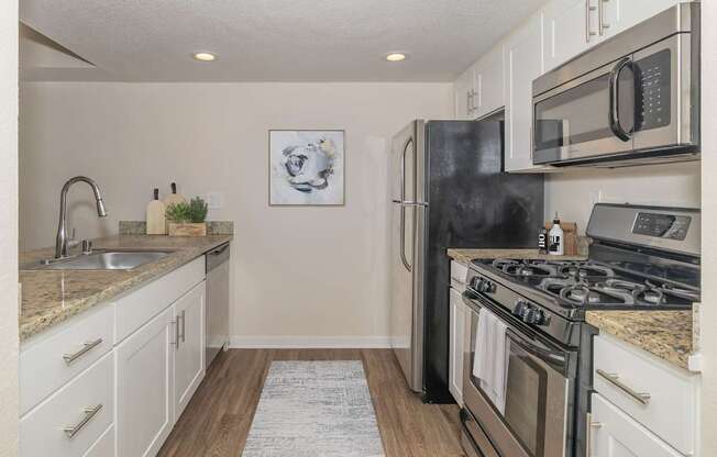 A kitchen with a black refrigerator, stove, and microwave.