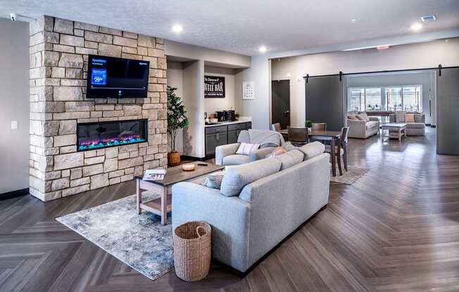A modern living room with a stone wall and a large grey sofa.