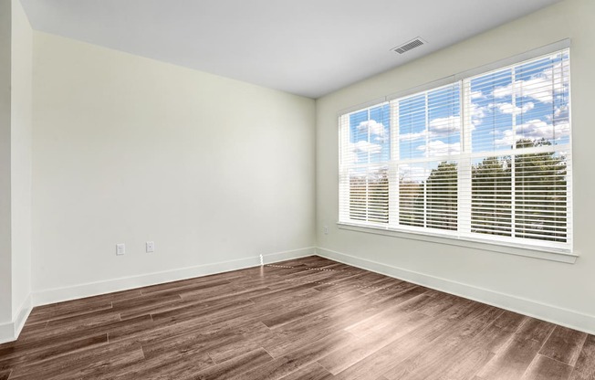A room with a window and wooden flooring.