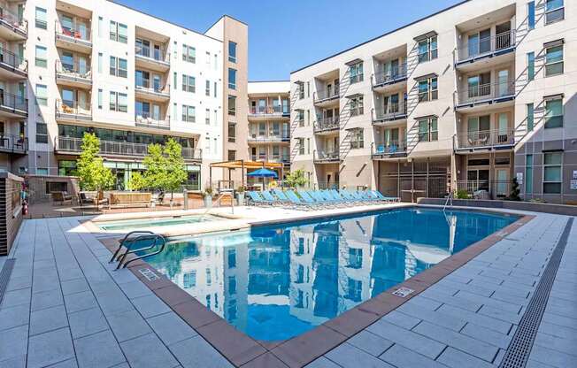 A large swimming pool in front of apartment buildings.