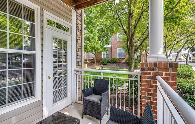 the front porch of a home with two chairs and a table