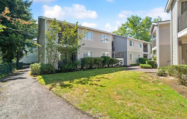 a pathway between two apartment buildings with grass and trees