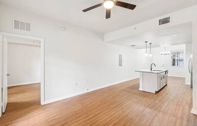 A room with a kitchen island and a ceiling fan.