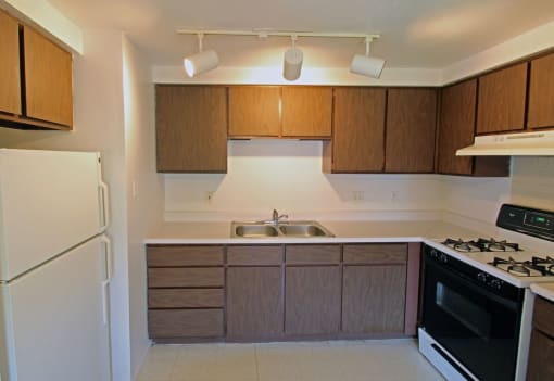 an empty kitchen with wooden cabinets and white appliances