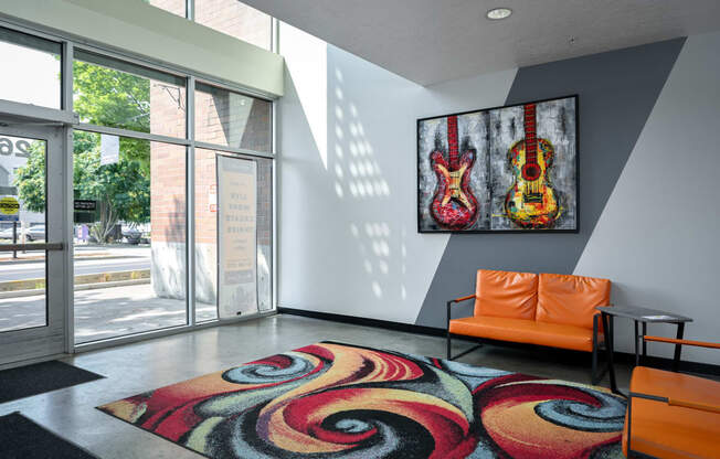 a living room with a colorful rug and a guitar painting on the wall