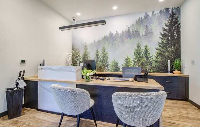A room with a desk, two chairs, and a large mural of a forest.