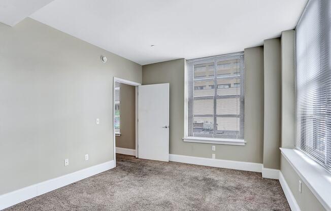 an empty living room with a large window and a door to a closet