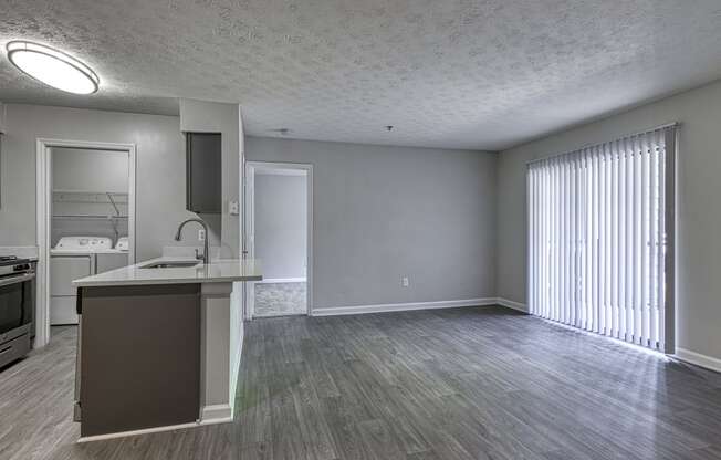 an empty living room and kitchen with a large window