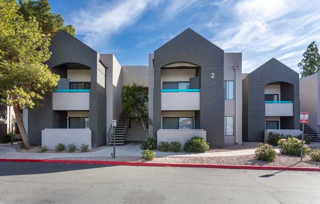 A modern building with a grey facade and a clear blue sky in the background.