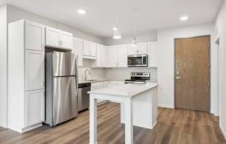 a white kitchen with stainless steel appliances and a white island