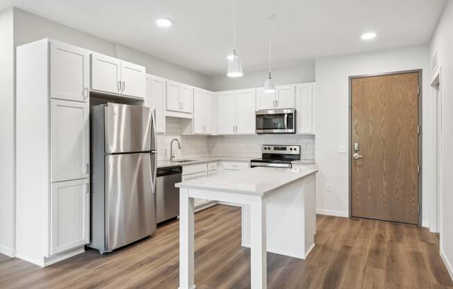 a white kitchen with stainless steel appliances and a white island