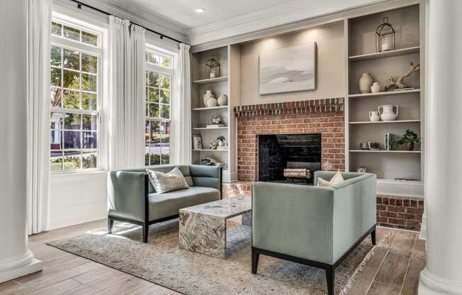 a living room with two green chairs and a brick fireplace