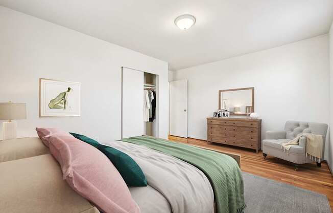 A bedroom with a bed, a dresser, a mirror, and a chair.