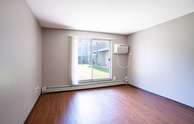 A room with a window and a wall-mounted air conditioner. Little Canada, MN Montreal Courts