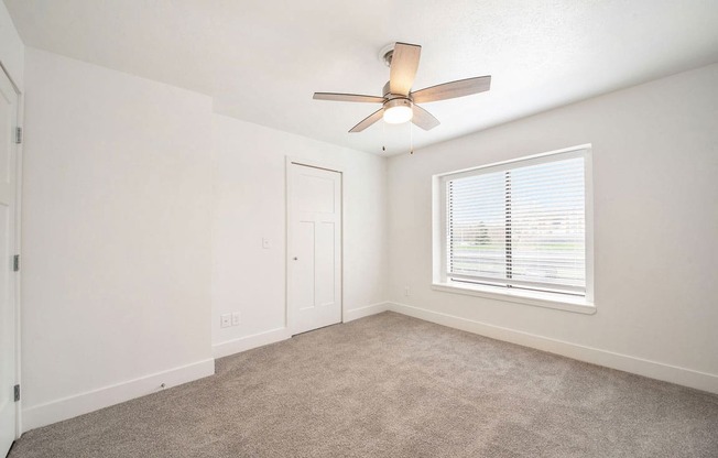 a bedroom with a ceiling fan and a window