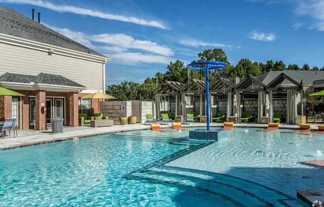 A large swimming pool with a blue umbrella and lounge chairs.