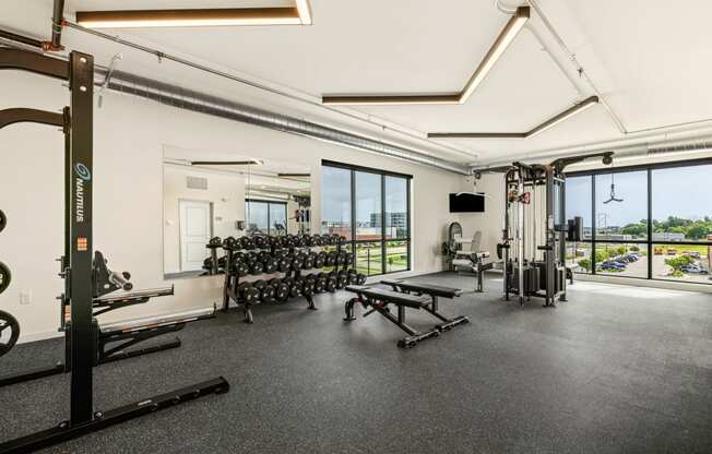 a gym with weights machines and windows and a view of the city at The Standard on 32nd, West Fargo, ND, 58078