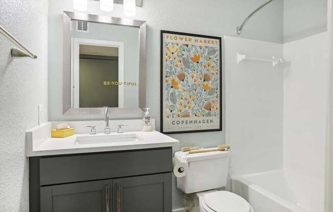 A bathroom with a toilet, sink, and poster.