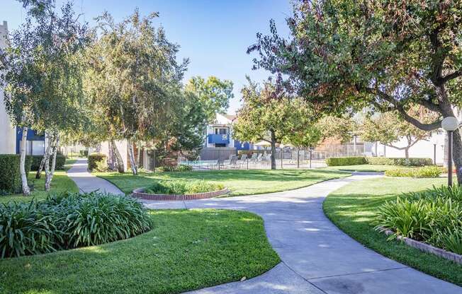 A tree-lined walkway curves through a well-kept park.