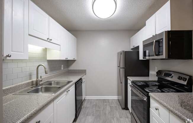 A kitchen with black appliances and white cabinets.
