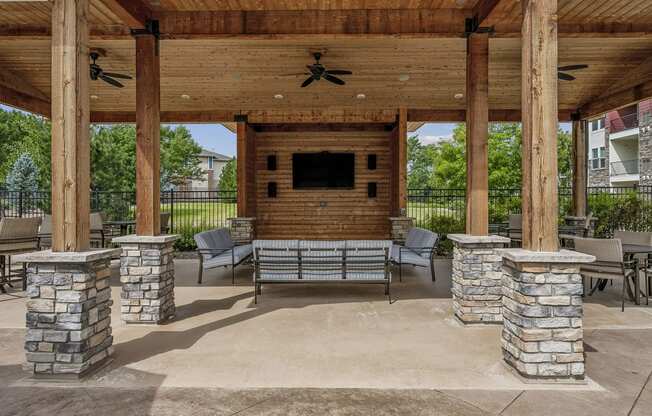 a covered patio with stone pillars and a fireplace