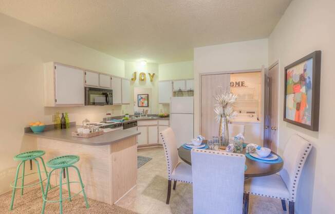 A kitchen with a bar stool and a dining table set for two.at Park at Forest Hill, Memphis, TN