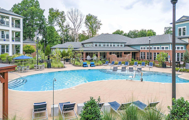 a swimming pool with chairs and a building in the background