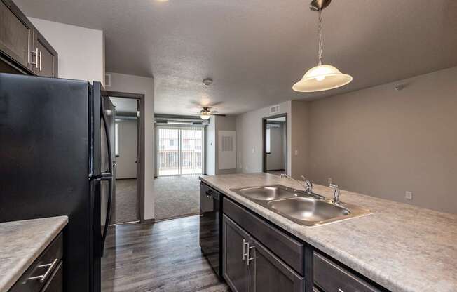 A kitchen with a black refrigerator and a marble countertop.