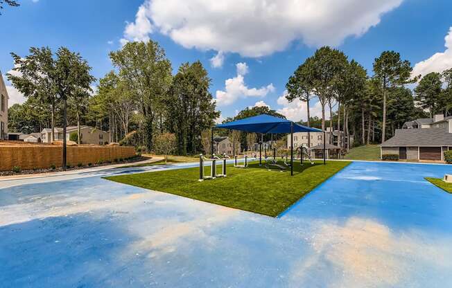 A playground with a blue surface and a white fence.