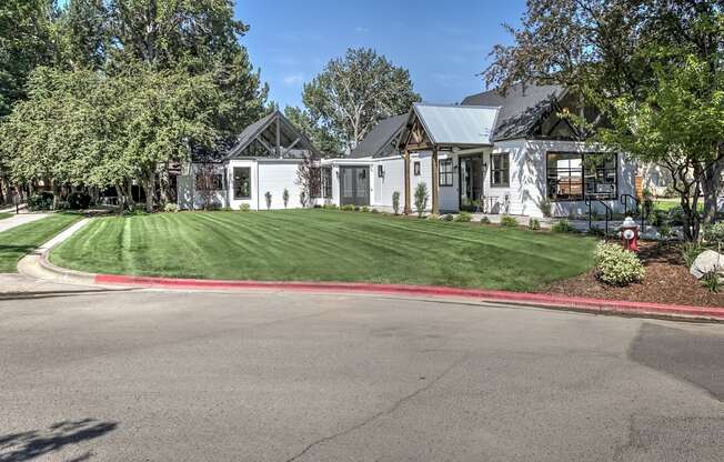 A white house with a grey roof and a green lawn in front.