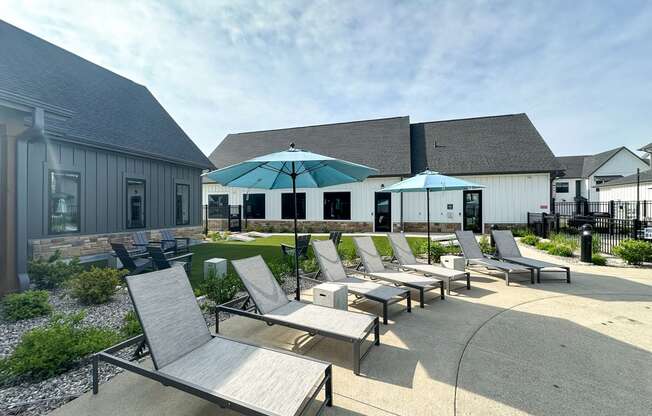 a patio with chairs and umbrellas in front of a building at The BLVD at Wilson Crossings, Wyoming Michigan