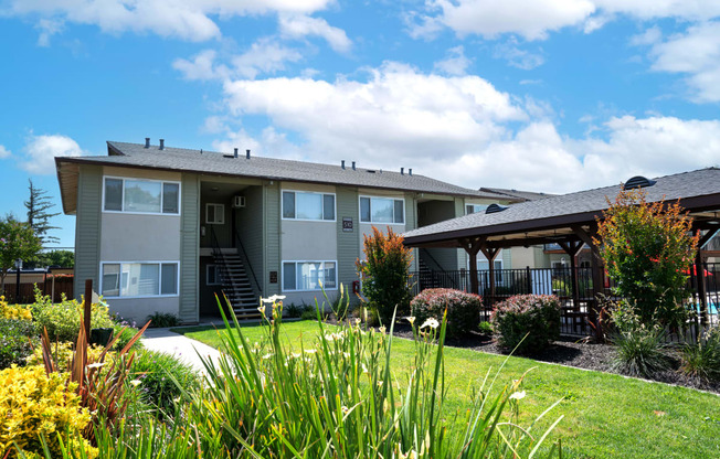 View of the well landscaped and blooming courtyard, exterior of buildings, and gated community pool area at Villas at Fair Oaks