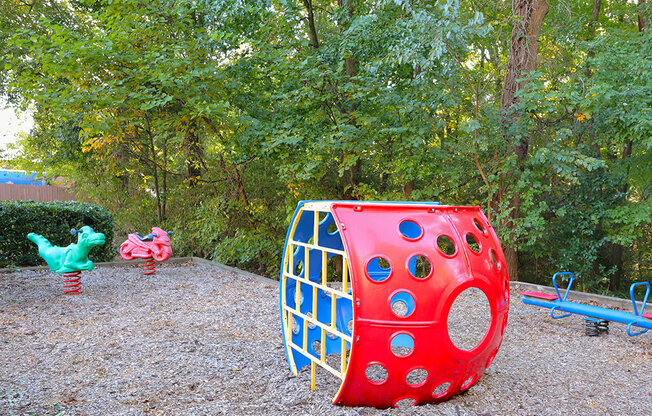 a red and blue toy house in a park