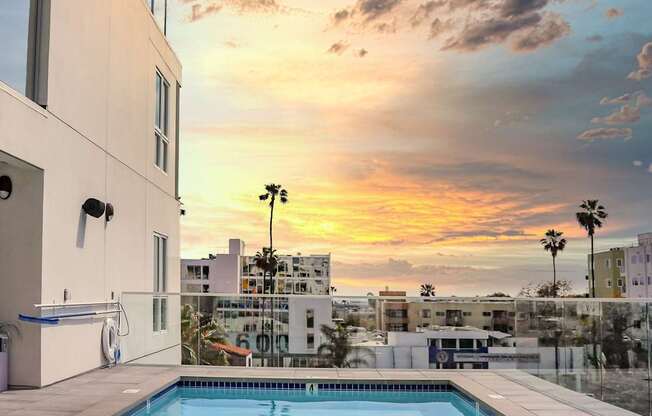 a view of the pool and sunset from a hotel room
