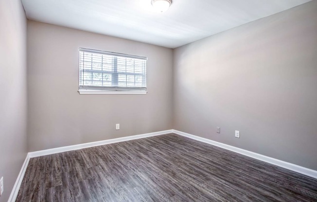 an empty room with wood floors and a window