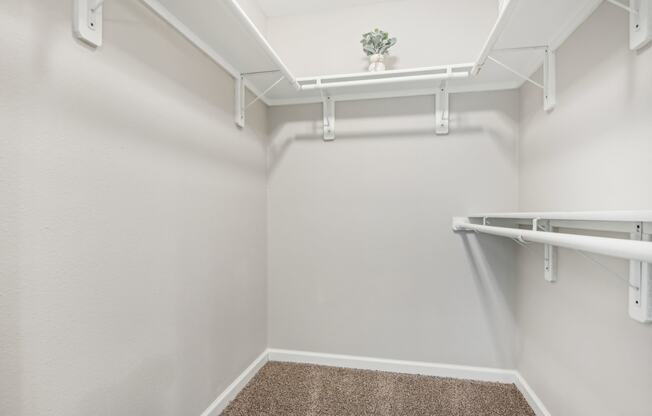 a spacious walk in closet in a home with white walls and a roll in shower