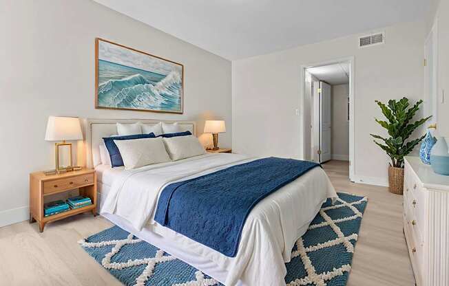 A bedroom with a large bed and a painting of a wave above it.