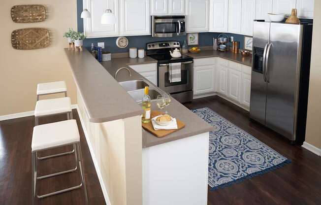 a kitchen with stainless steel appliances and a long counter top at The Winhall of Williams Pointe Apartments, Waukee