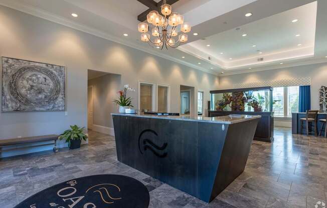 A reception area with a black reception desk and a chandelier hanging from the ceiling.