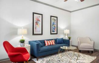A living room with a blue couch, a red chair, and a white chair.